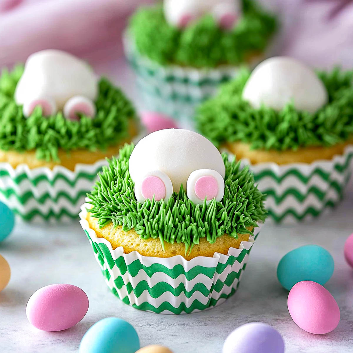 Fluffy marshmallows placed on grass-like green frosting.