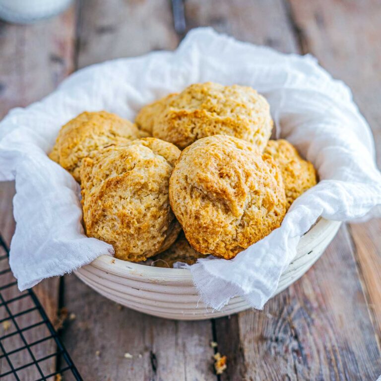 Buttermilk drop biscuits placed on a lined bannaton over a wooden surface.