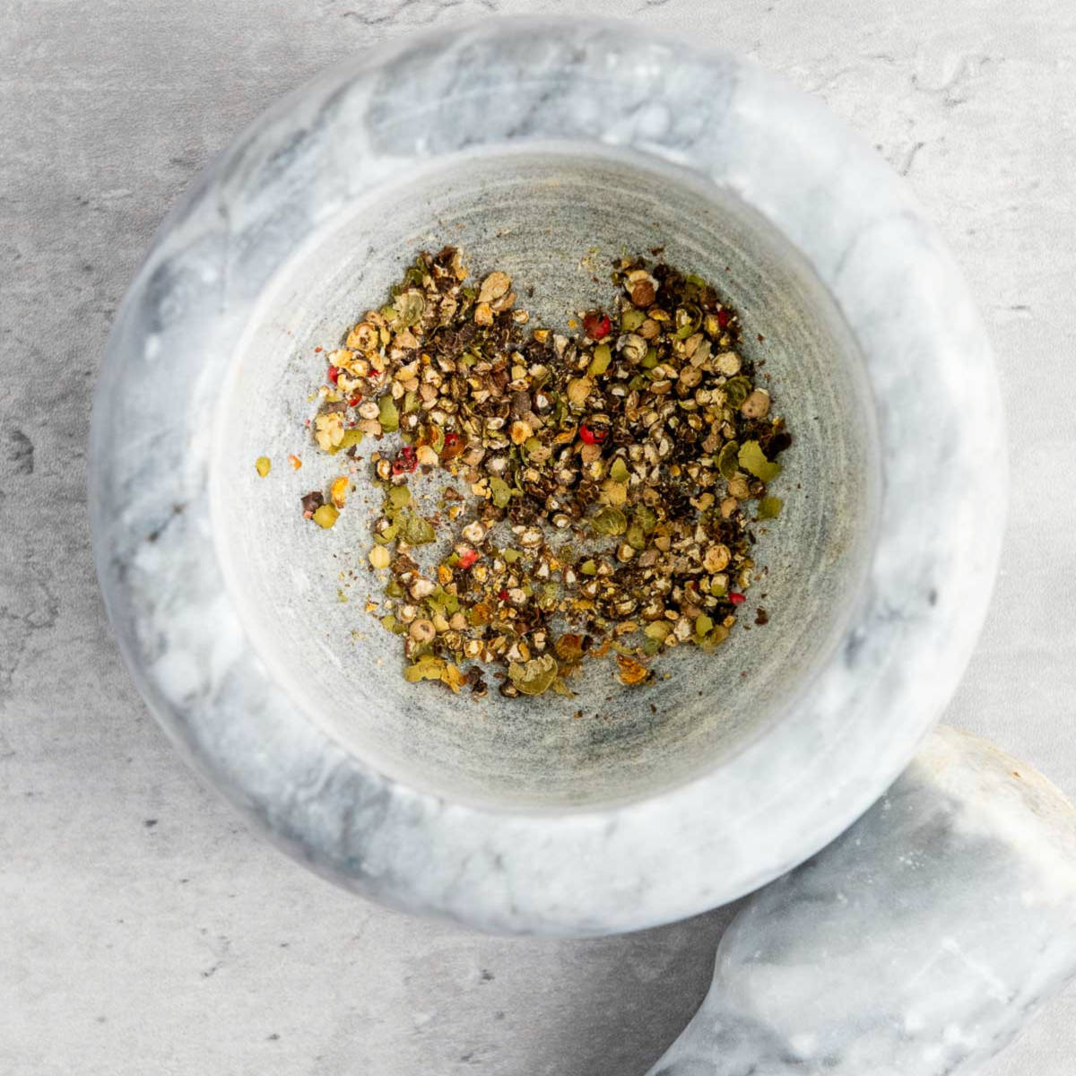 Coarsly crushed peppercorns in a mortar and pestle.