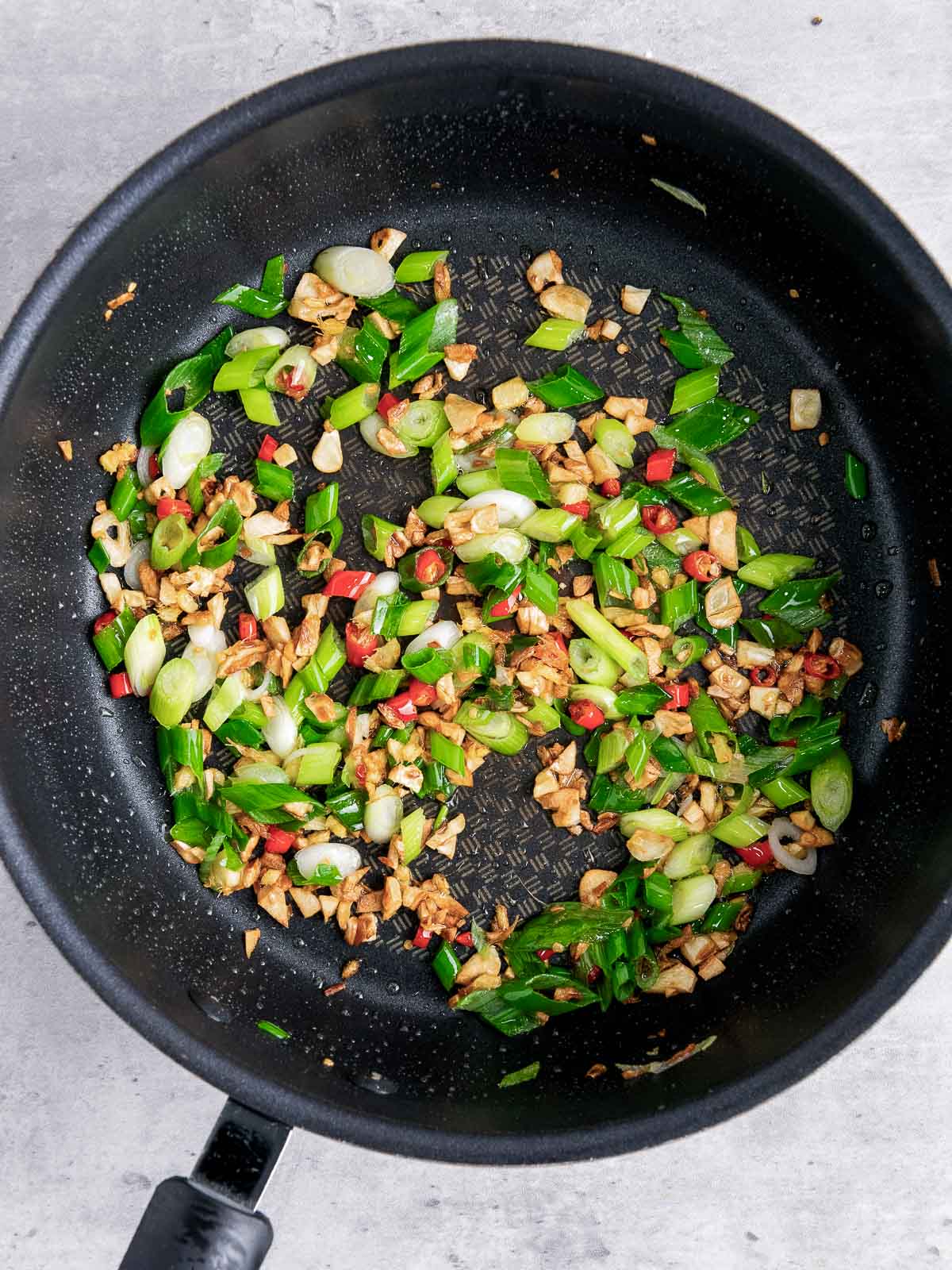 Sauted ginger, garlic, chili pepper, and scallion in a skillet.