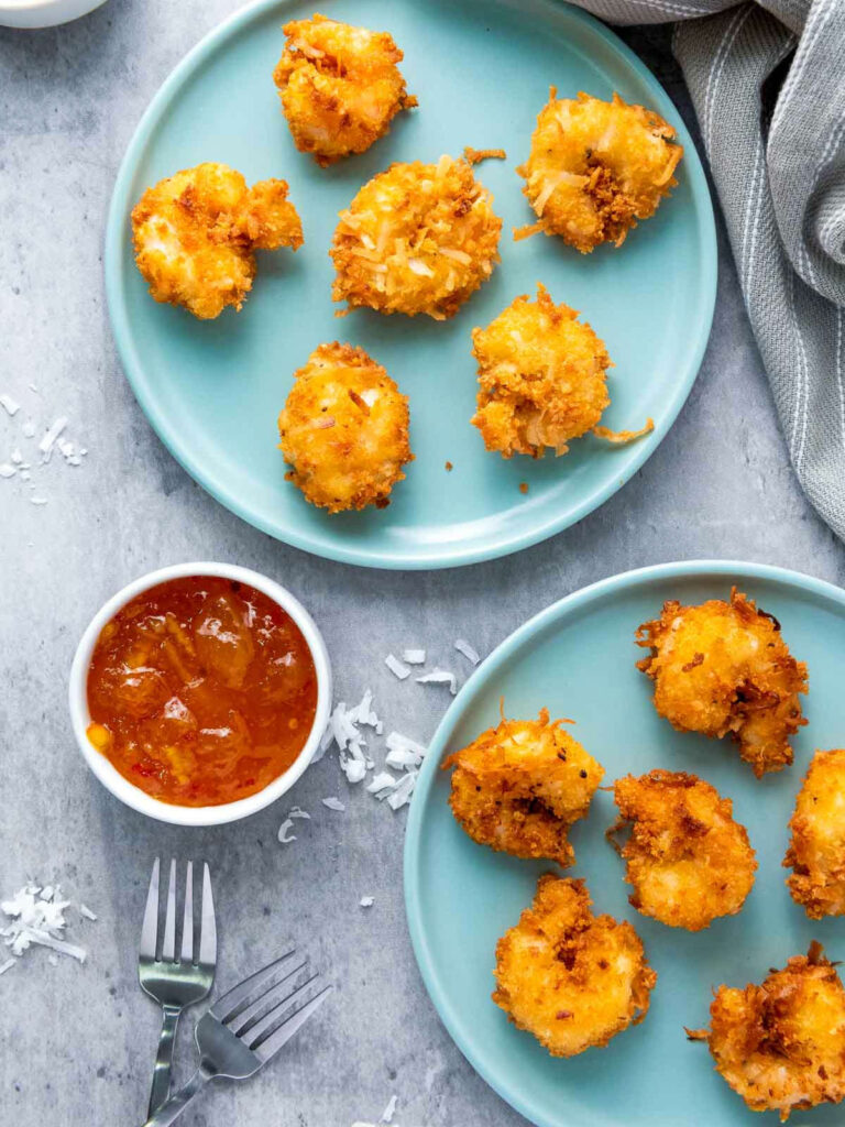 Two plates of coconut shrimp served with chili orange dip.