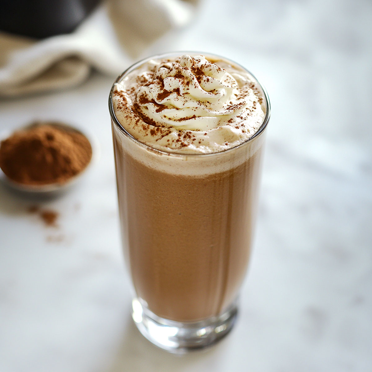 Homemade coffee frappe in a glass topped with whipped cream.