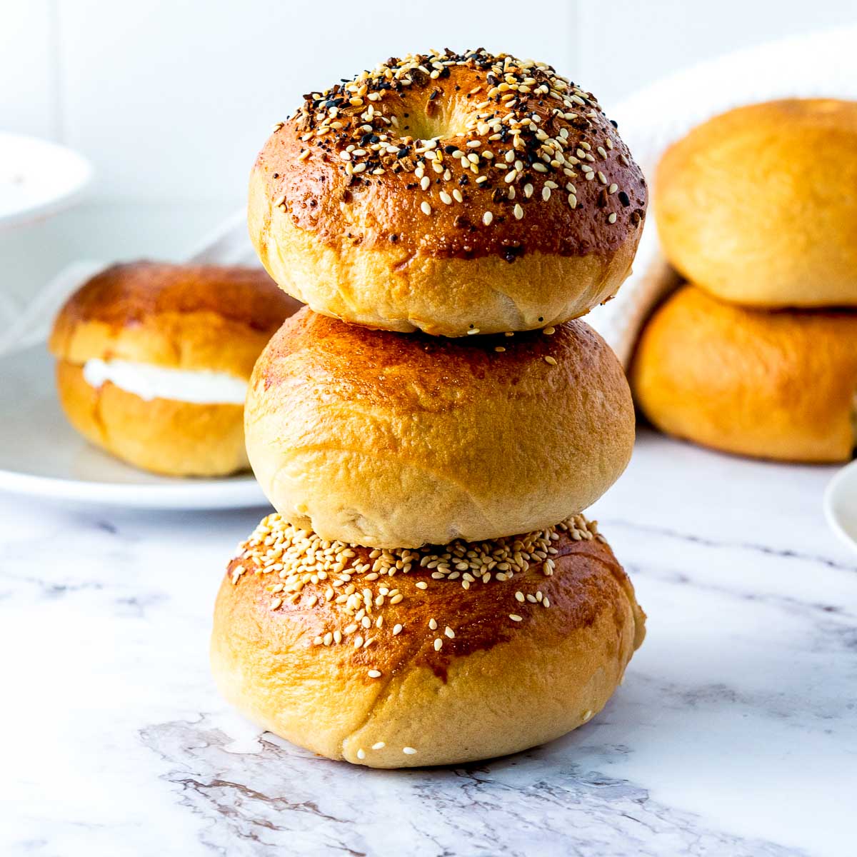 Homemade bagels stacked on each other and placed on a marble surface.