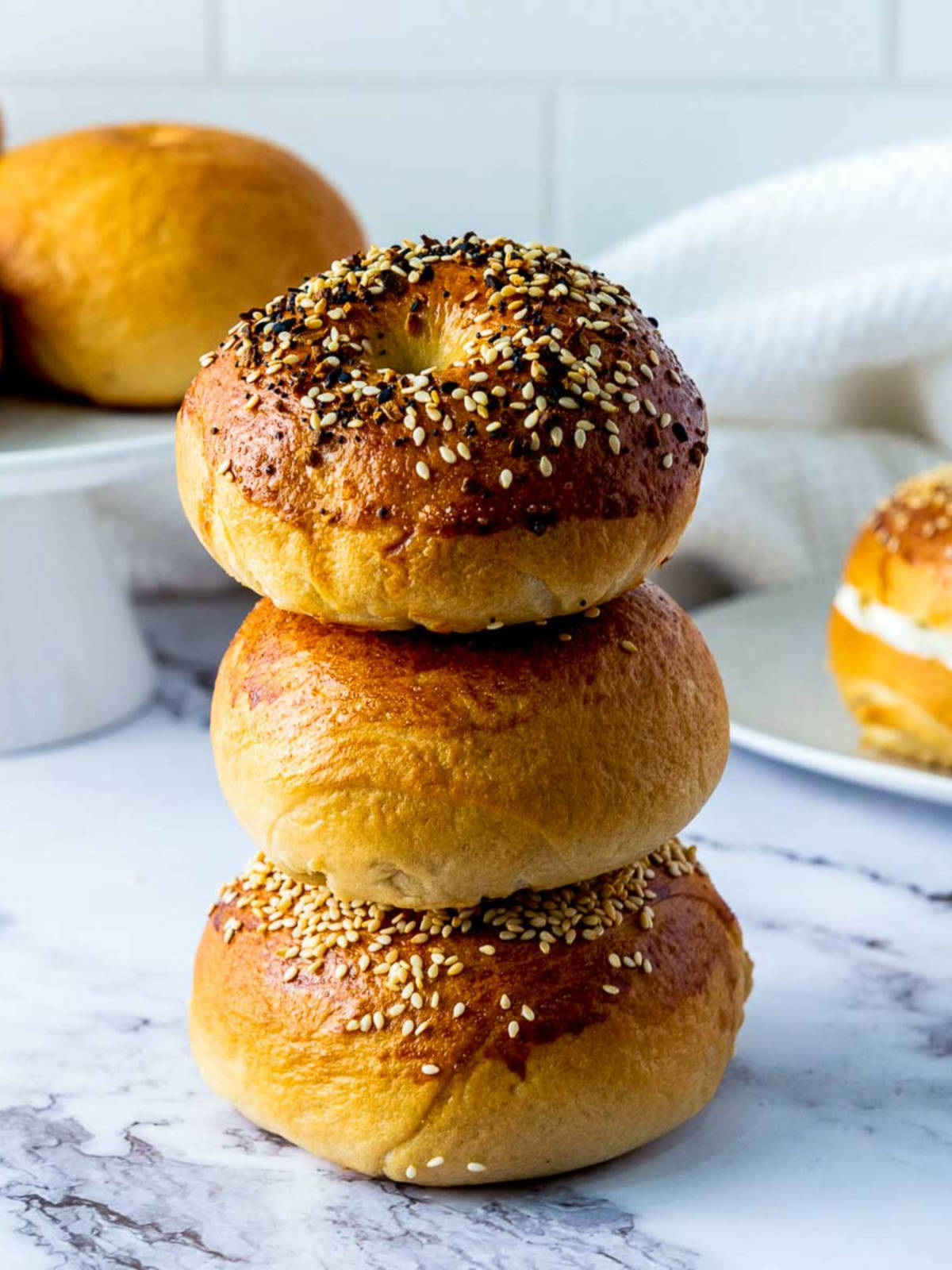 A stack of three bagels with more bagels in the background.