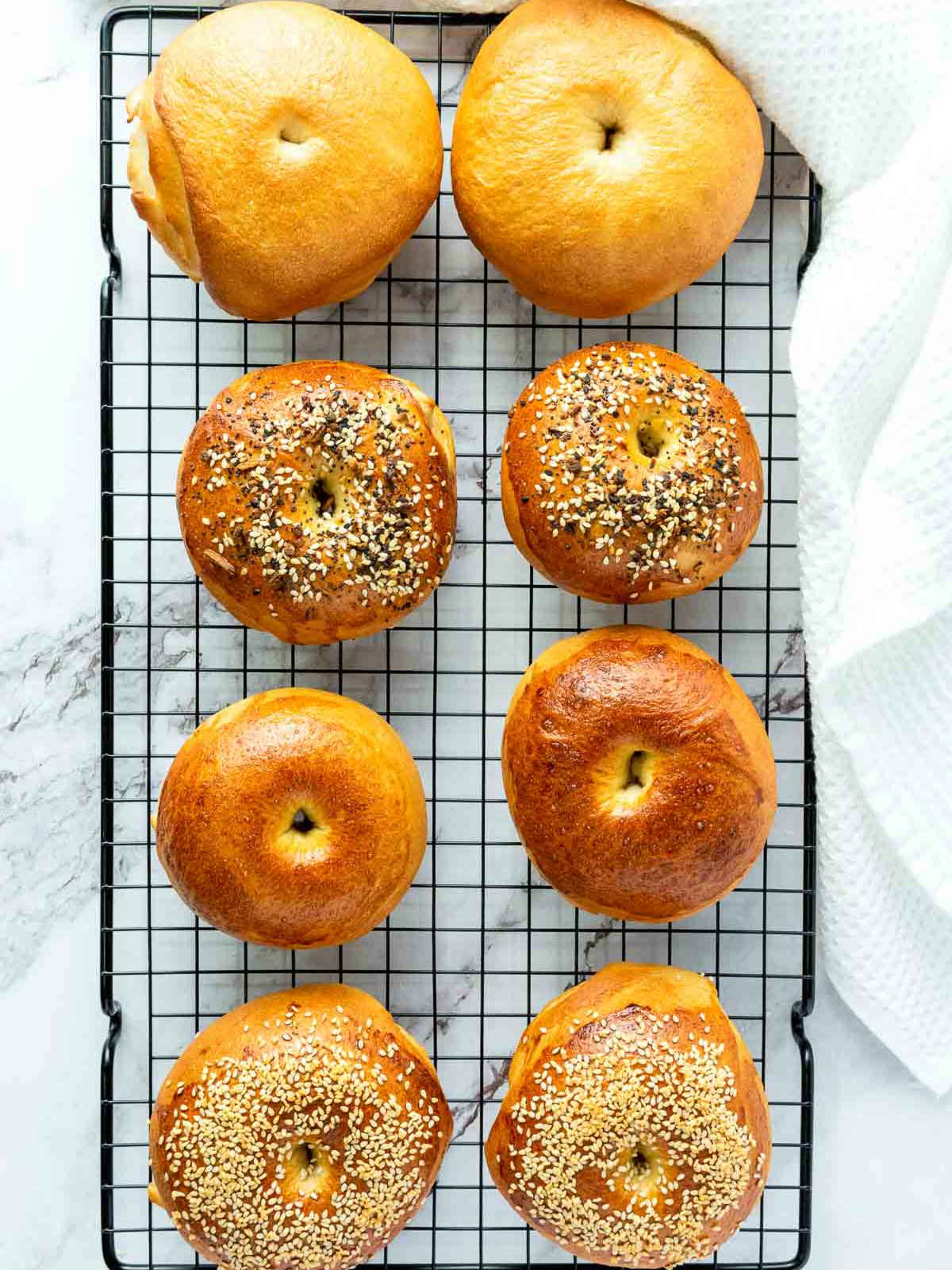 Perfectly baked bagels on a wire rack.