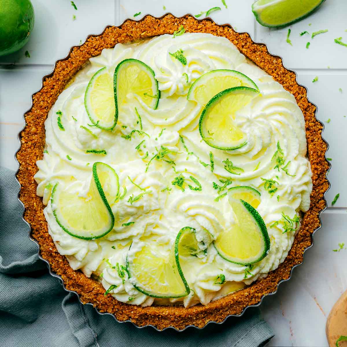 Key lime pie topped with whipped cream and lime slices.