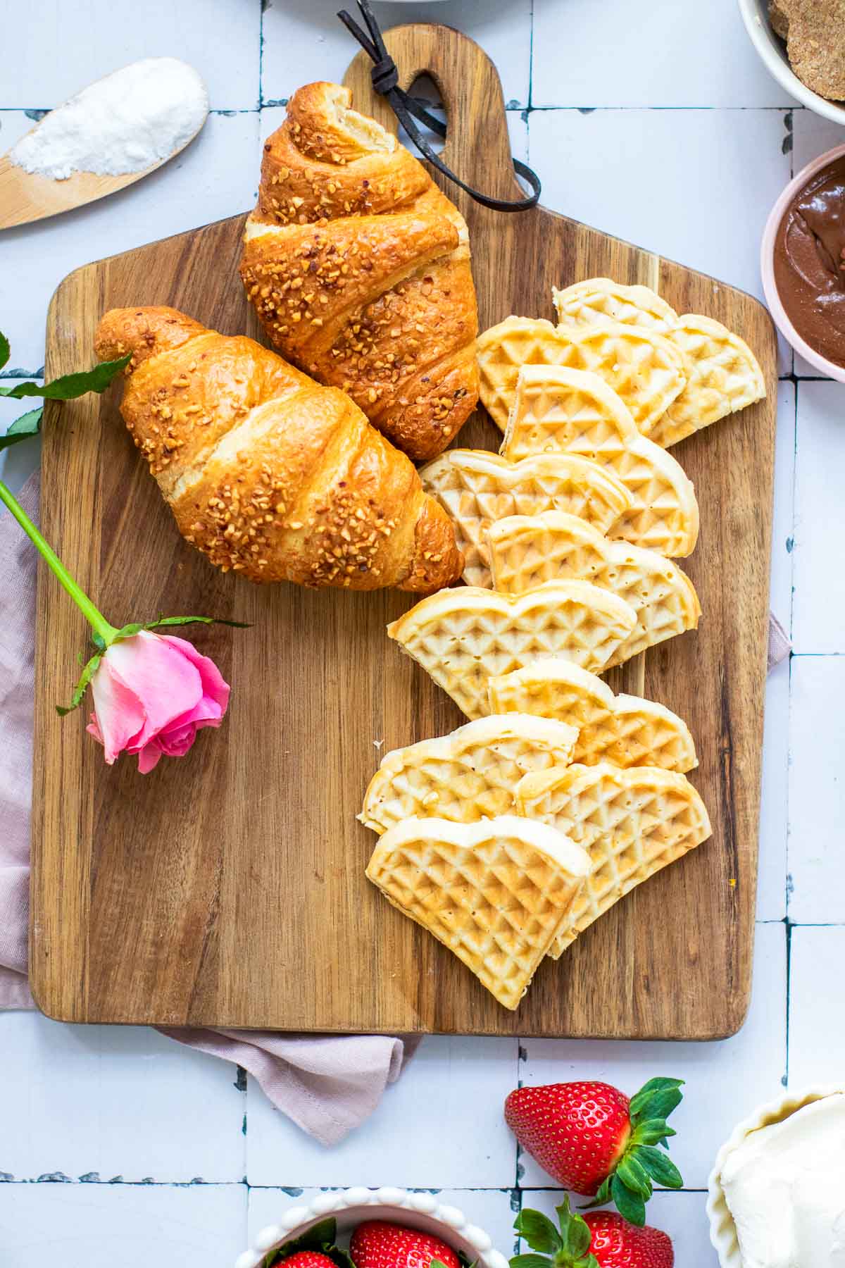 Waffles and croissants placed on the board for assembly.