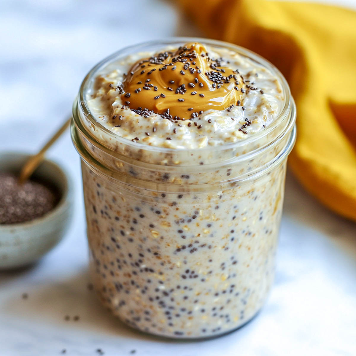 A jar of overnight oats topped with almond butter and chia seeds.