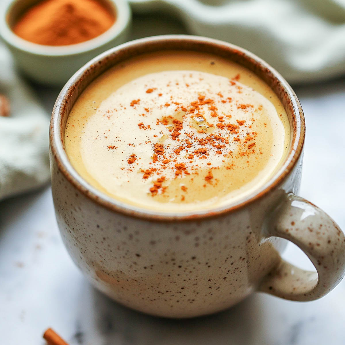 Pumpkin spice protein coffee on a white marble surface.