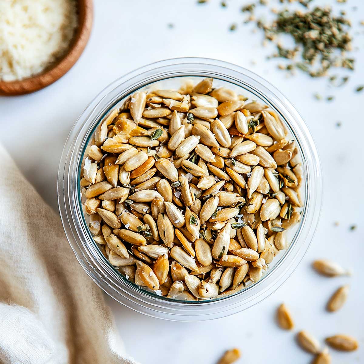 Roasted sunflower seeds in a bowl with parmesan in the background.