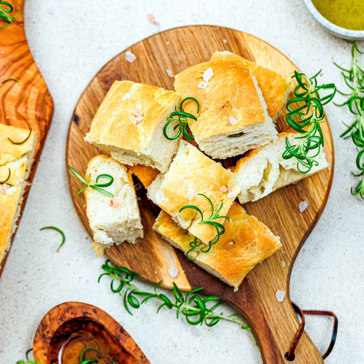 Rosemary focaccia cut into small pieces and placed on a wooden board.