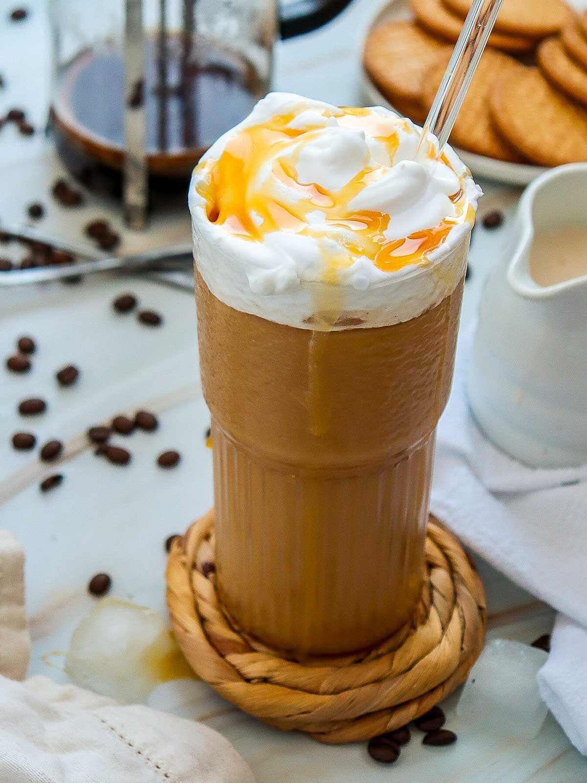 A tall glass of caramel iced coffee on a marble surface.