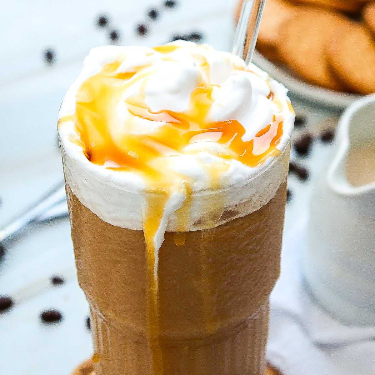 Close up of caramel iced coffee glass topped with whipped cream and caramel.