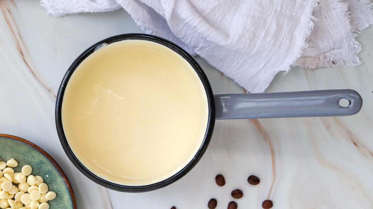 Homemade syrup in a saucepan placed on a marble surface.