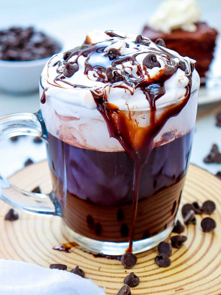 Mocha hot chocolate mug placed on a small wooden board with chocolate chips in the background.