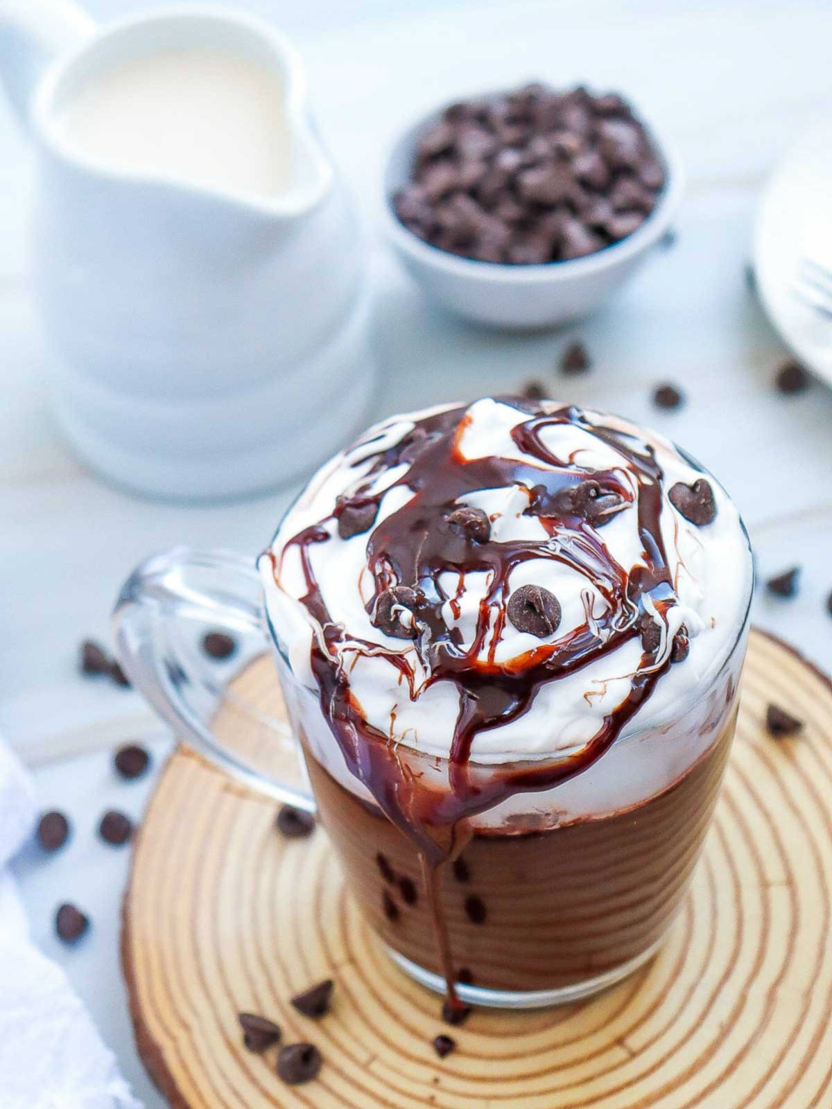 Mocha hot chocolate mug with milk and chocolate chips in the background.