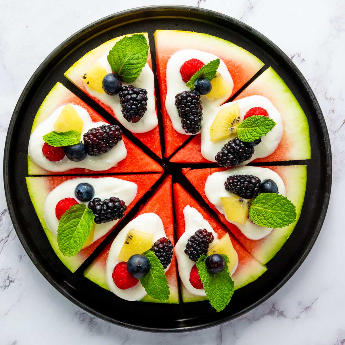 Fully assembled watermelon pizza with fruit toppings.