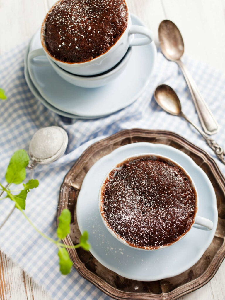 Two microwave chocolate mug cakes on a white surface.