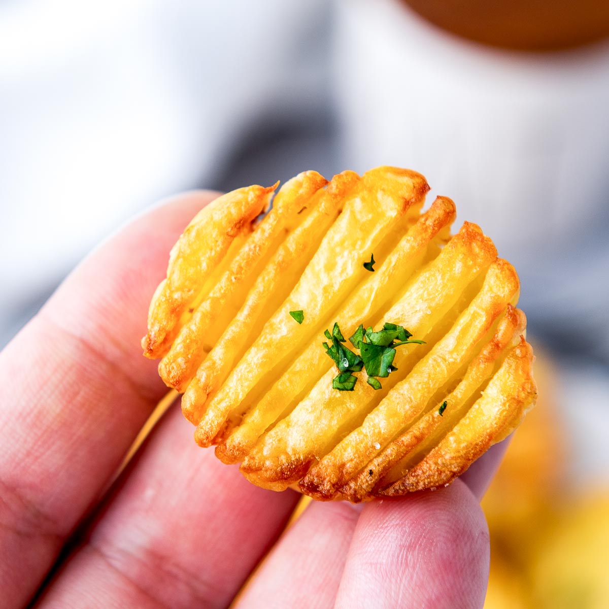 Person holding a slice of accordion potato.