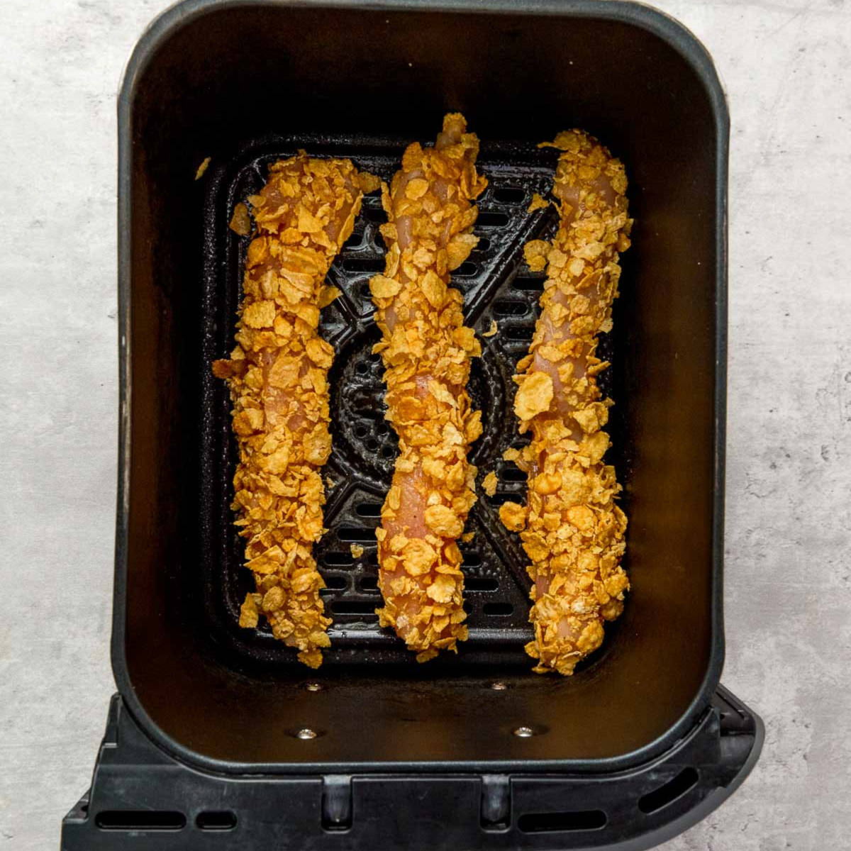 Coated chicken placed in air fryer basket.