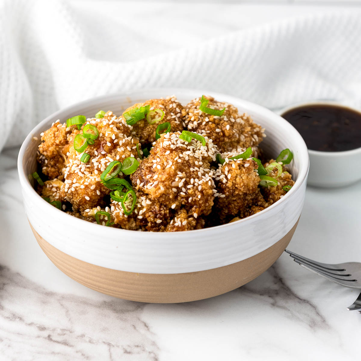 A bowl of air fryer teriyaki cauliflower wings with a small bowl of teriyaki sauce in the background.