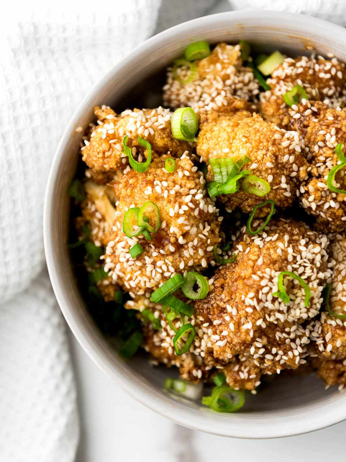 Close up of tariyaki cauliflower wings placed on a marble surface.