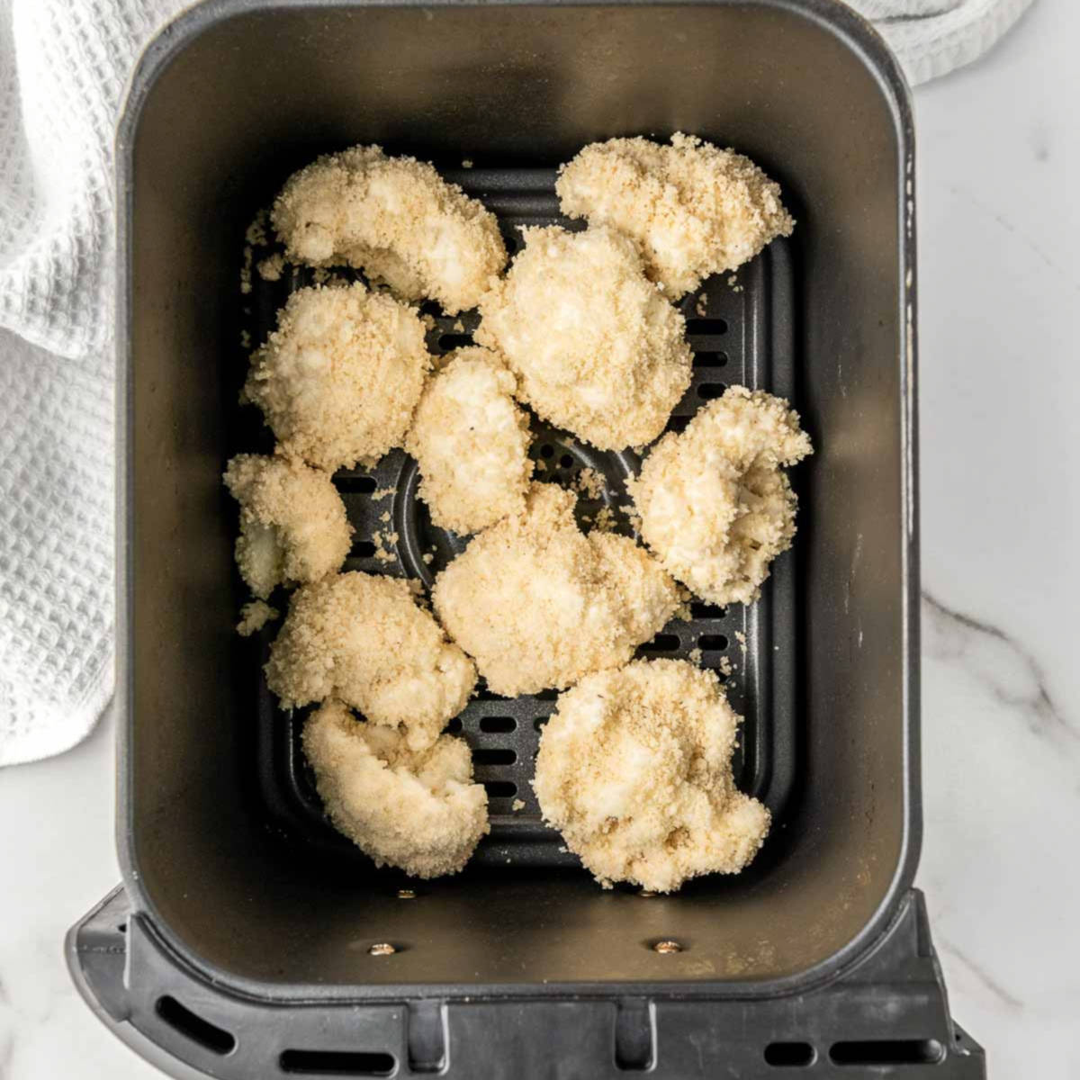 Coated florets in air fryer basket.
