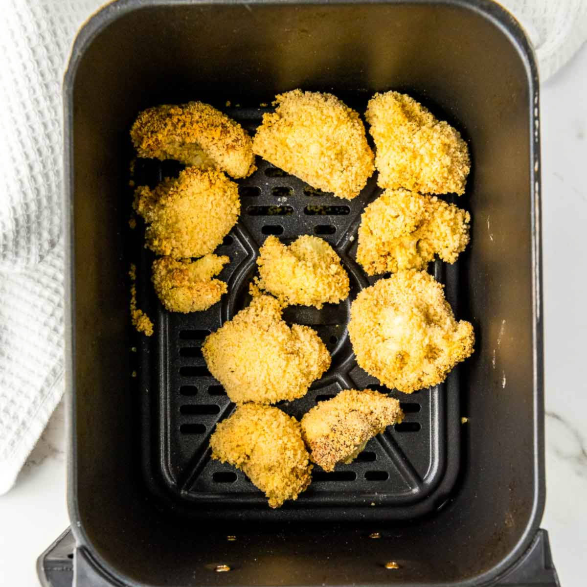 Roasted cauliflower wings in air fryer basket.