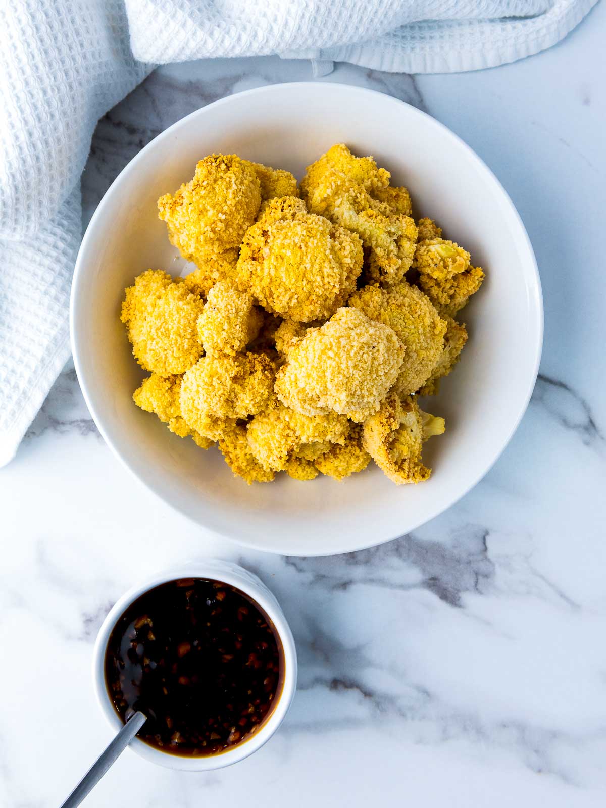 Roasted cauliflower wings and teriyaki sauce in two bowls.