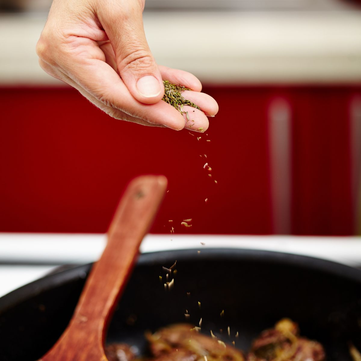 A person sprinkling spices to a dish.