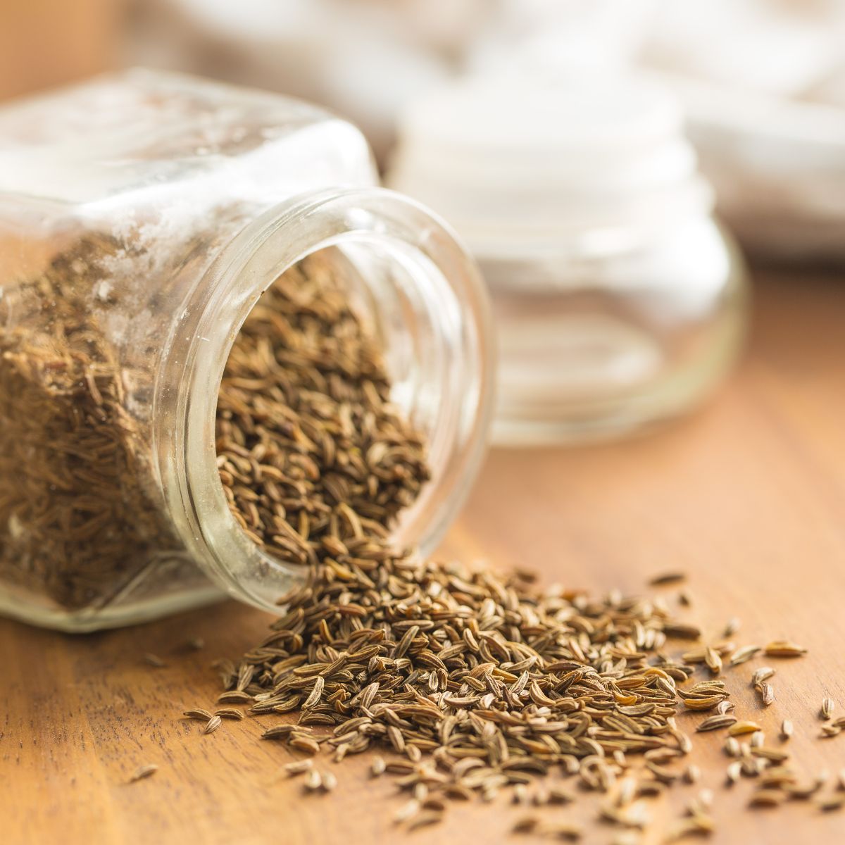Cumin seeds spilling from a jar.