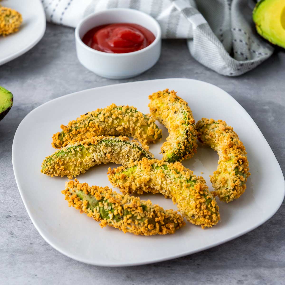 Side view of a avocado fries placed on a white serving plates.