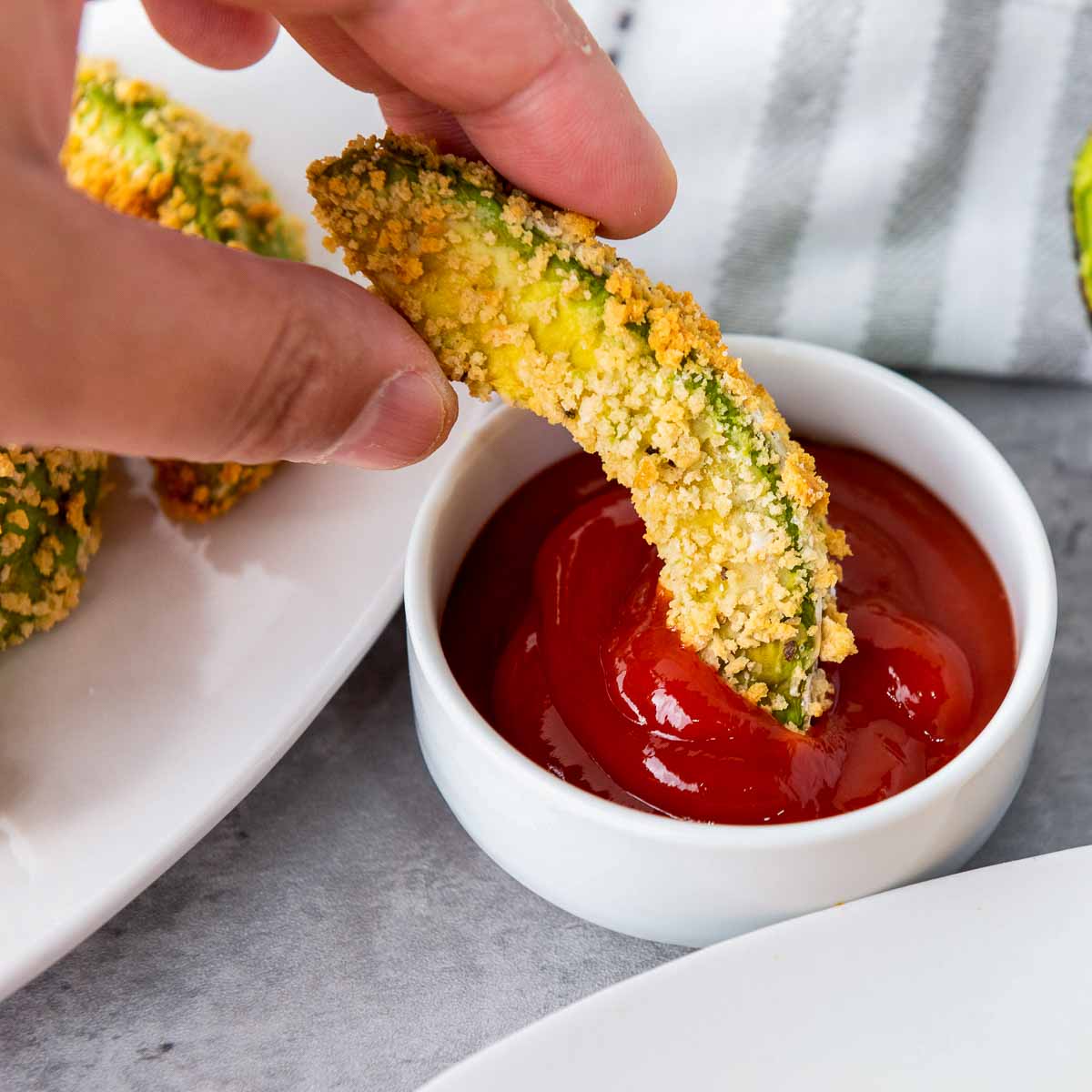 An avocado fries dipped in ketchup.