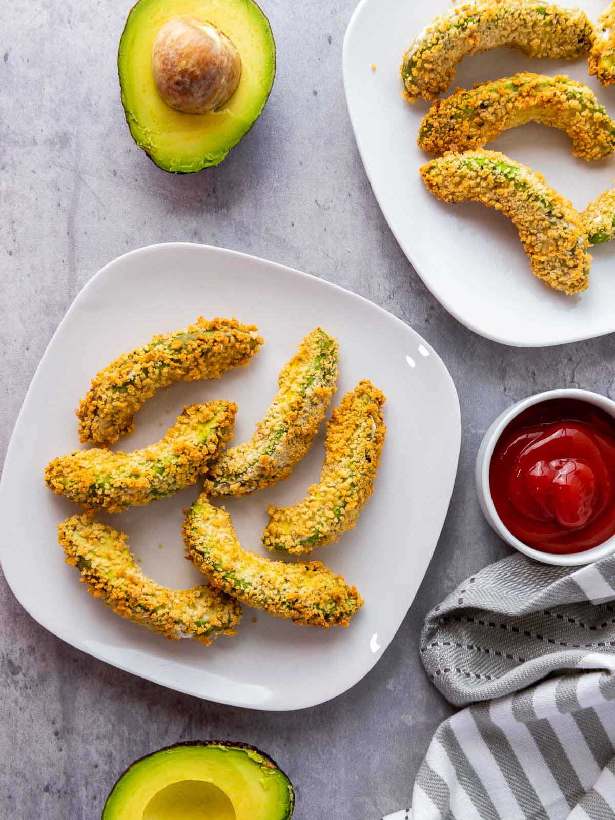 Top view two plates of avocado fries served with ketchup.