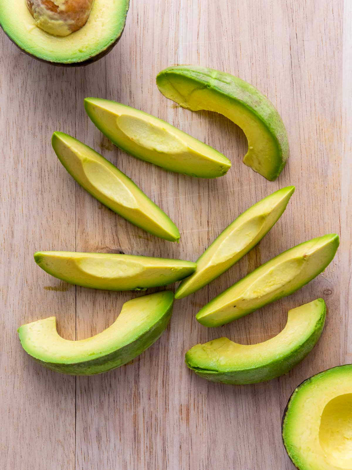 Thick cut avo slices on a wooden board.