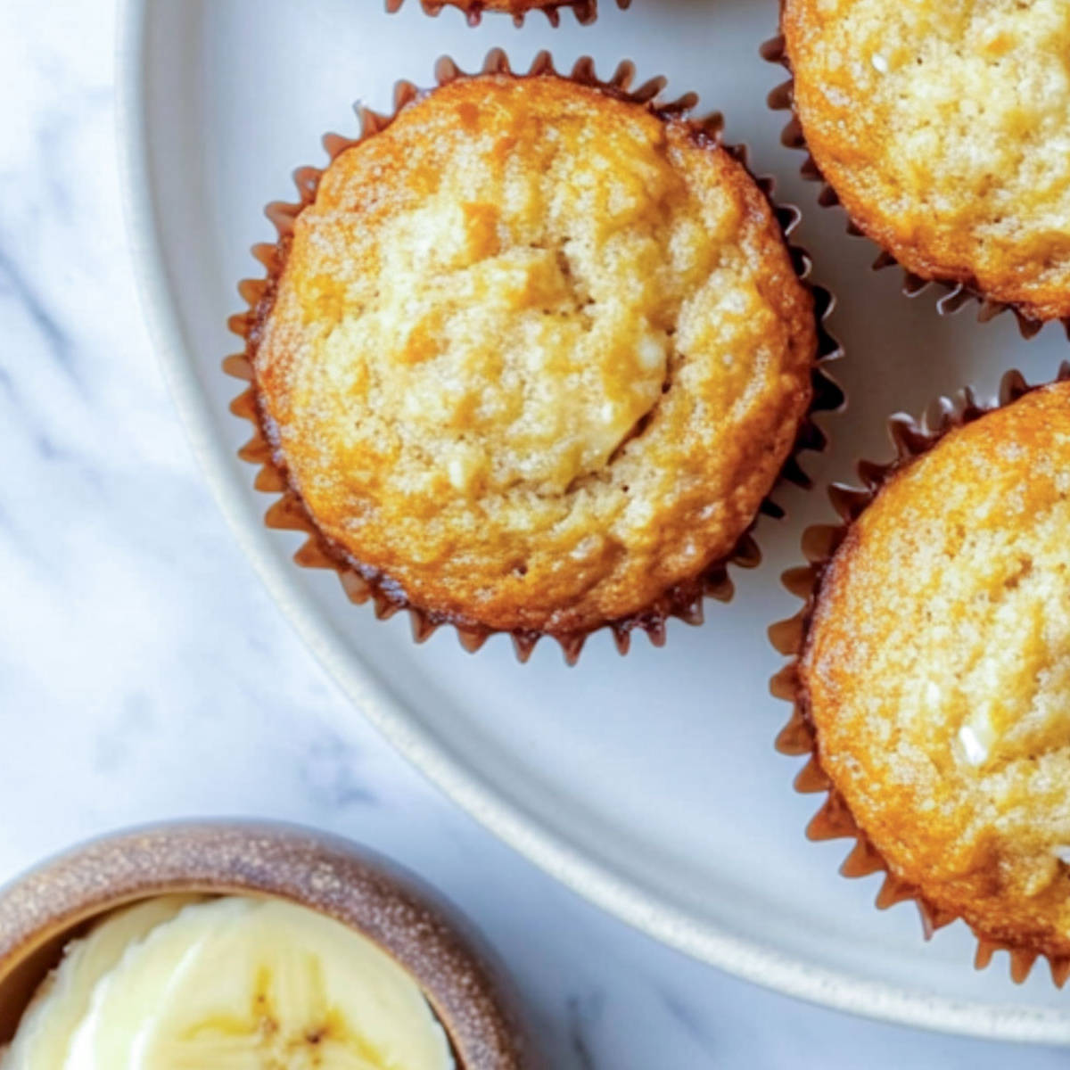 Close up of a banana cottage cheese muffin with sliced bananas in the background.