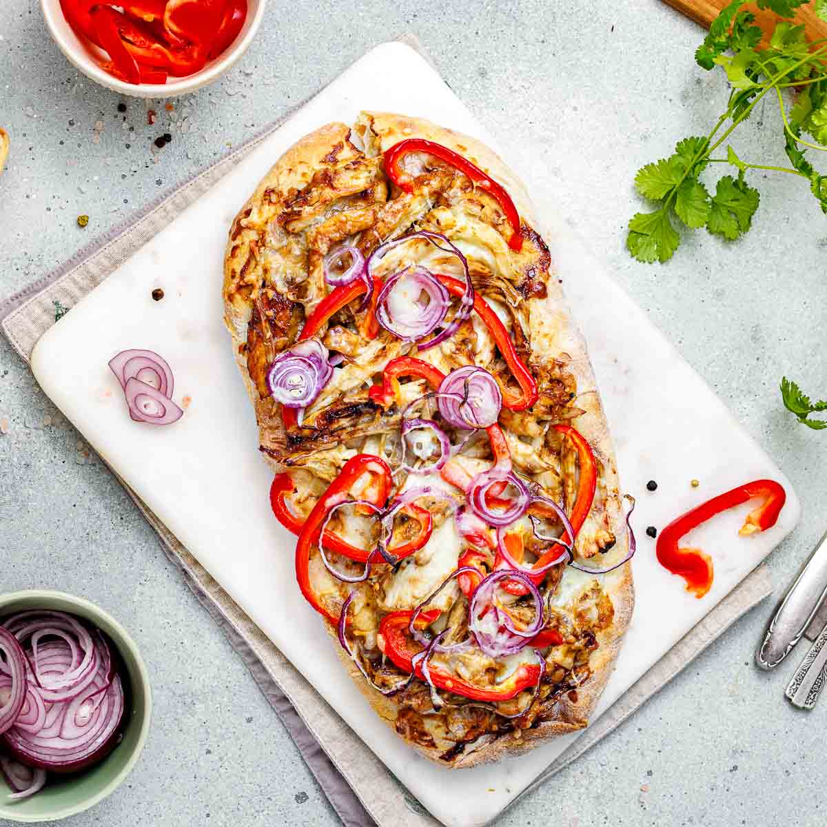 Top view of bbq chicken flatbread placed on a grey surface.