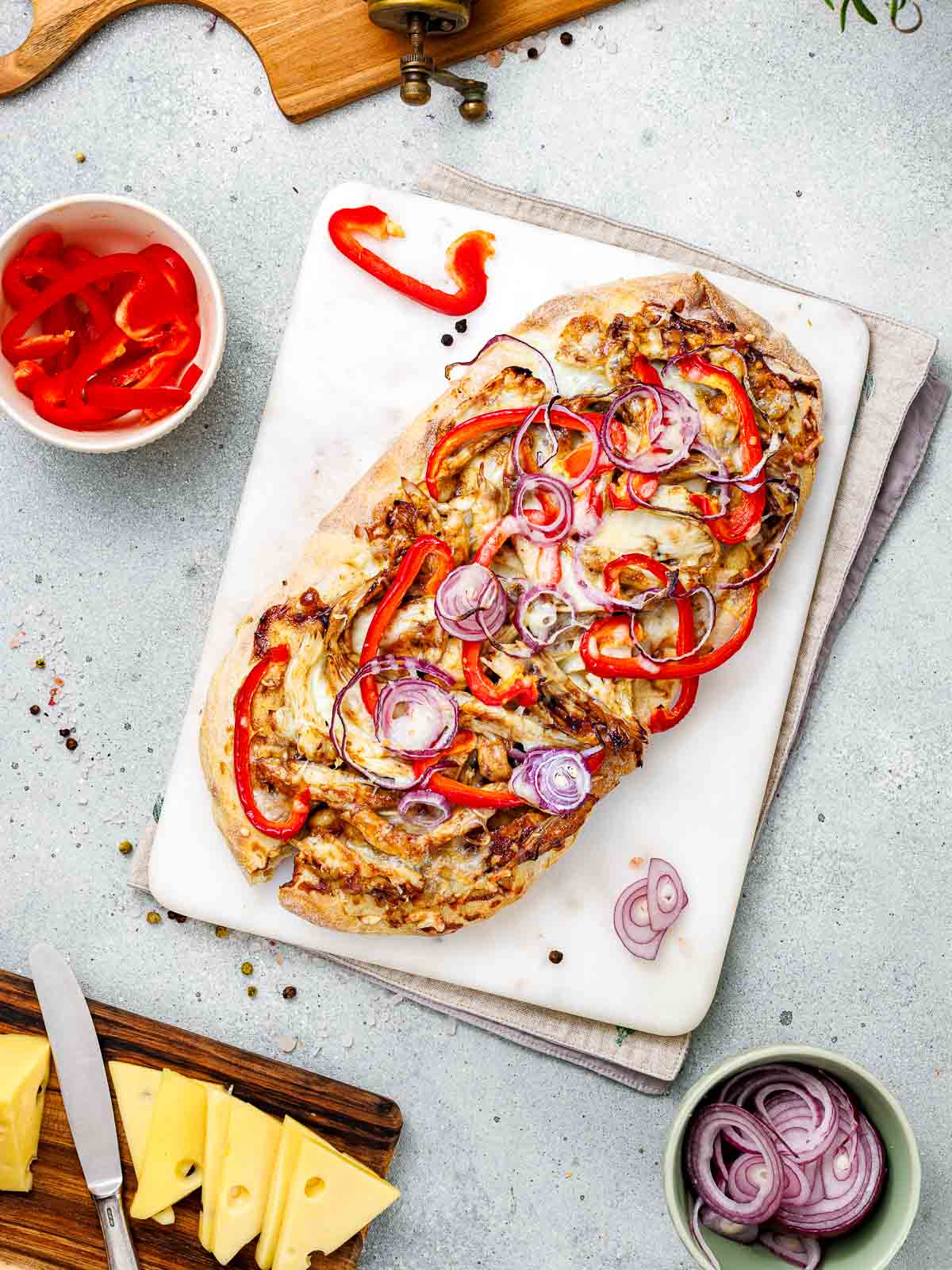 Bbq chicken flatbread on a white board with cheese slices in the background.