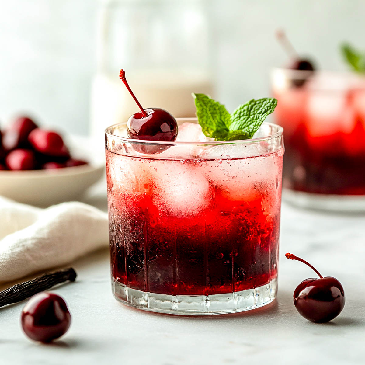 Side view of cherry vanilla mocktail glass on a white marble surface.