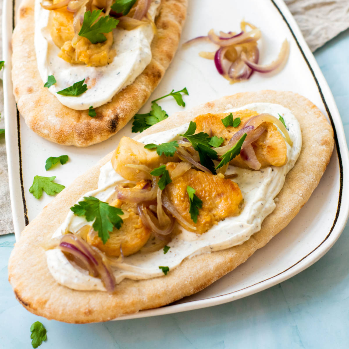 Close up of chicken pita on a white serving board.
