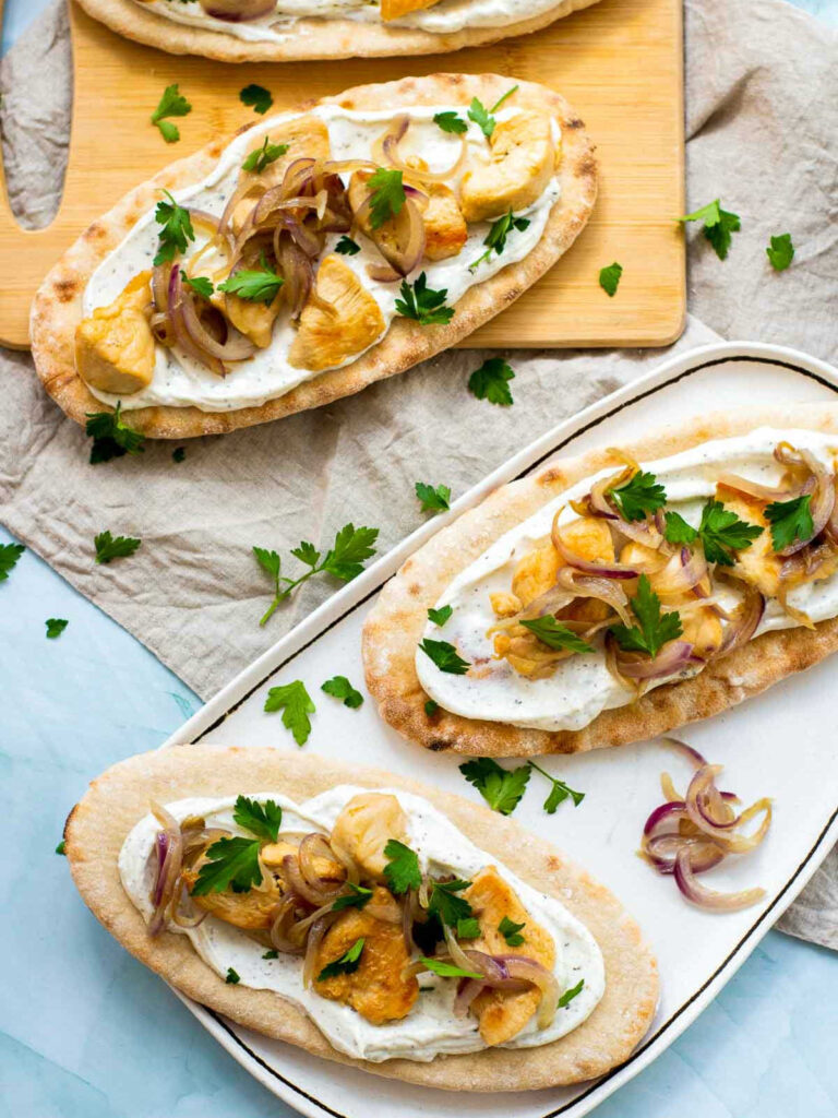 Chicken pitas served on a white serving plate and on wooden boards.