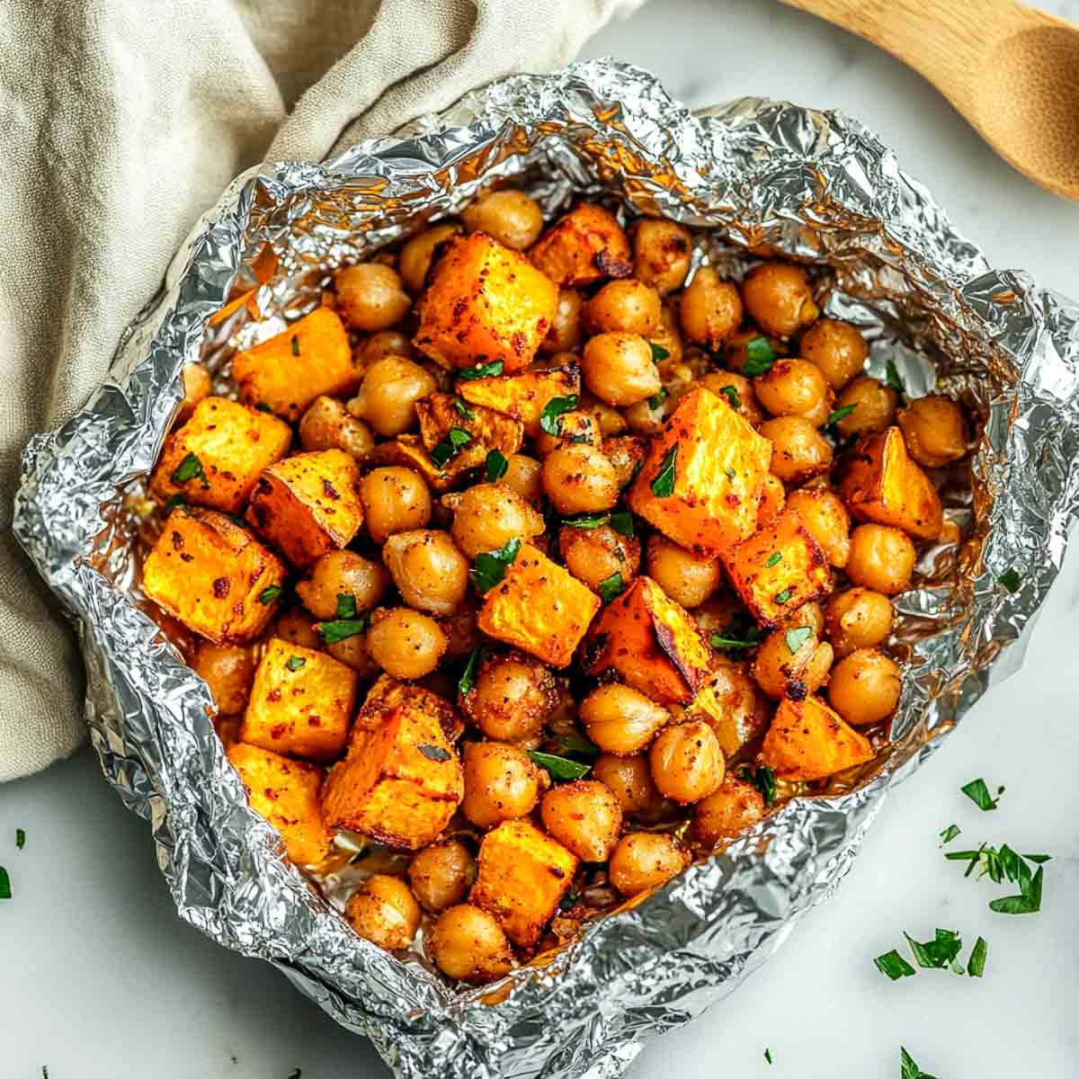 Chickpeas and sweet potato cubes in a foil package after roasting.