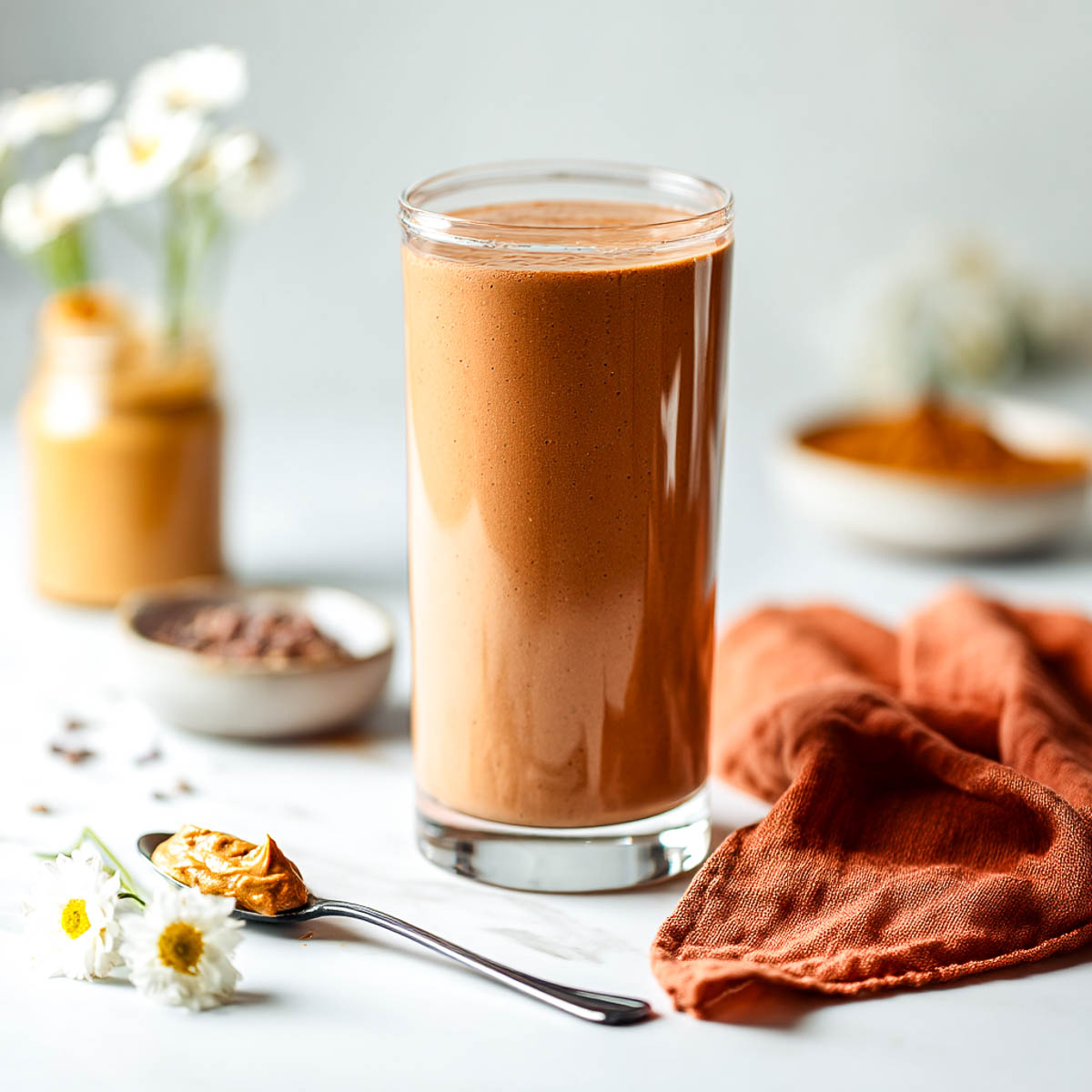 Chocolate peanut butter smoothie with banana and cacao on marble surface.