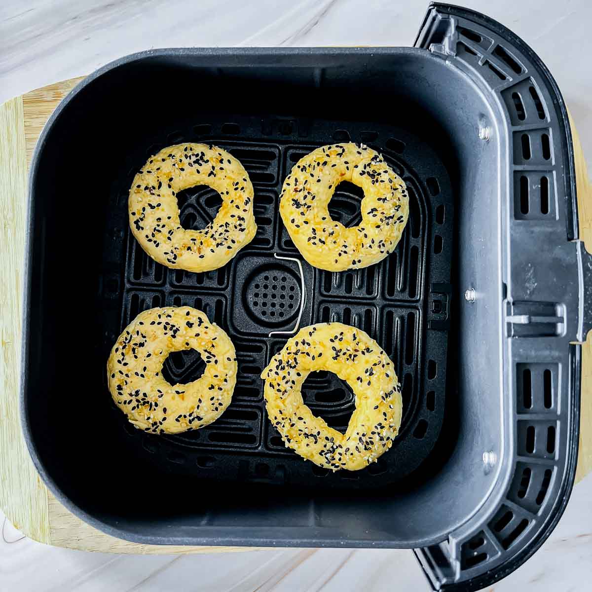Bagels placed in the air fryer basket.