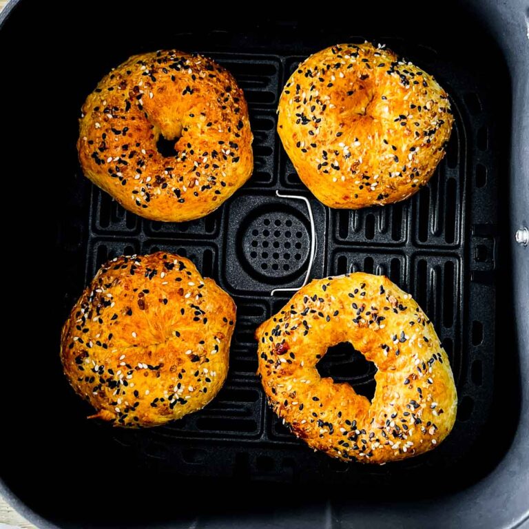Perfectly cooked bagels in air fryer basket.