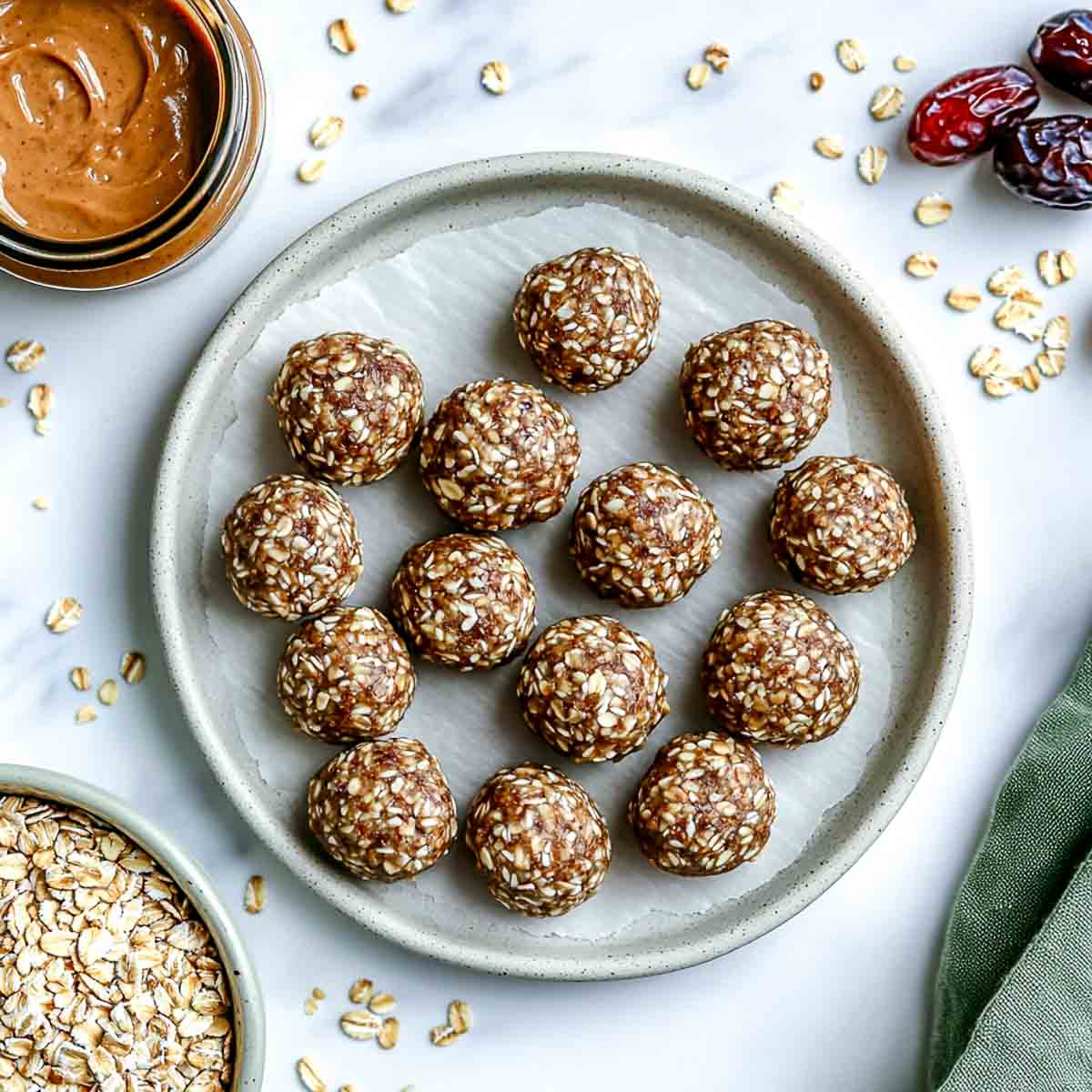 Light grey plate with hemp seed almond butter energy bites and oats scattered.