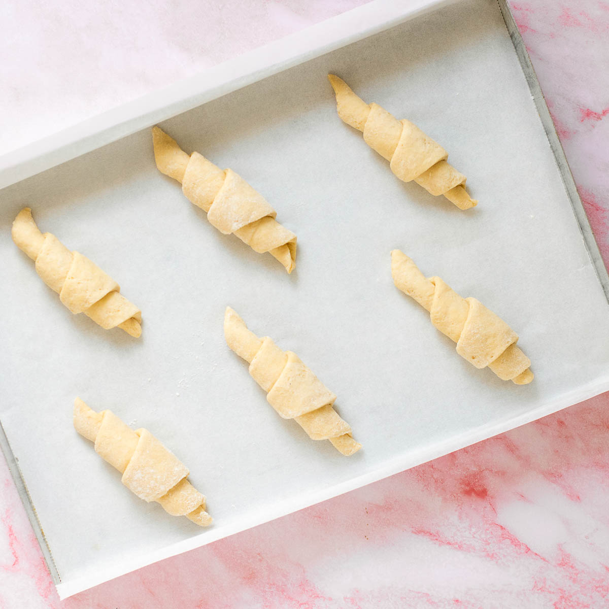 Shaped croissants placed on a lined baking tray.