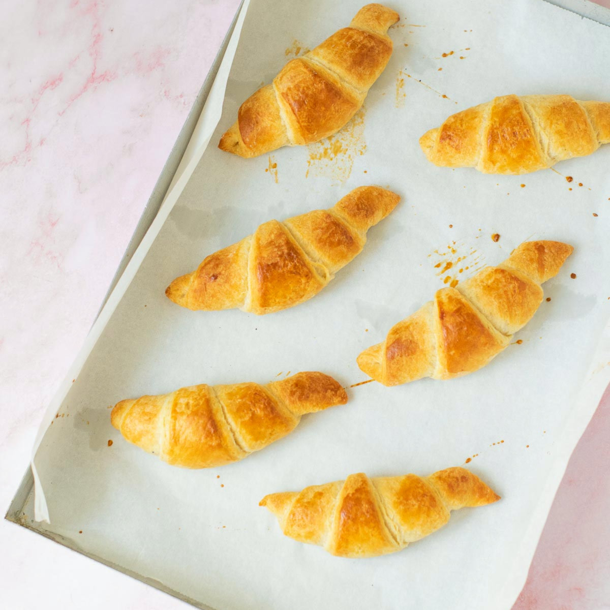 Homemade croissant baked and cooling on the baking tray.