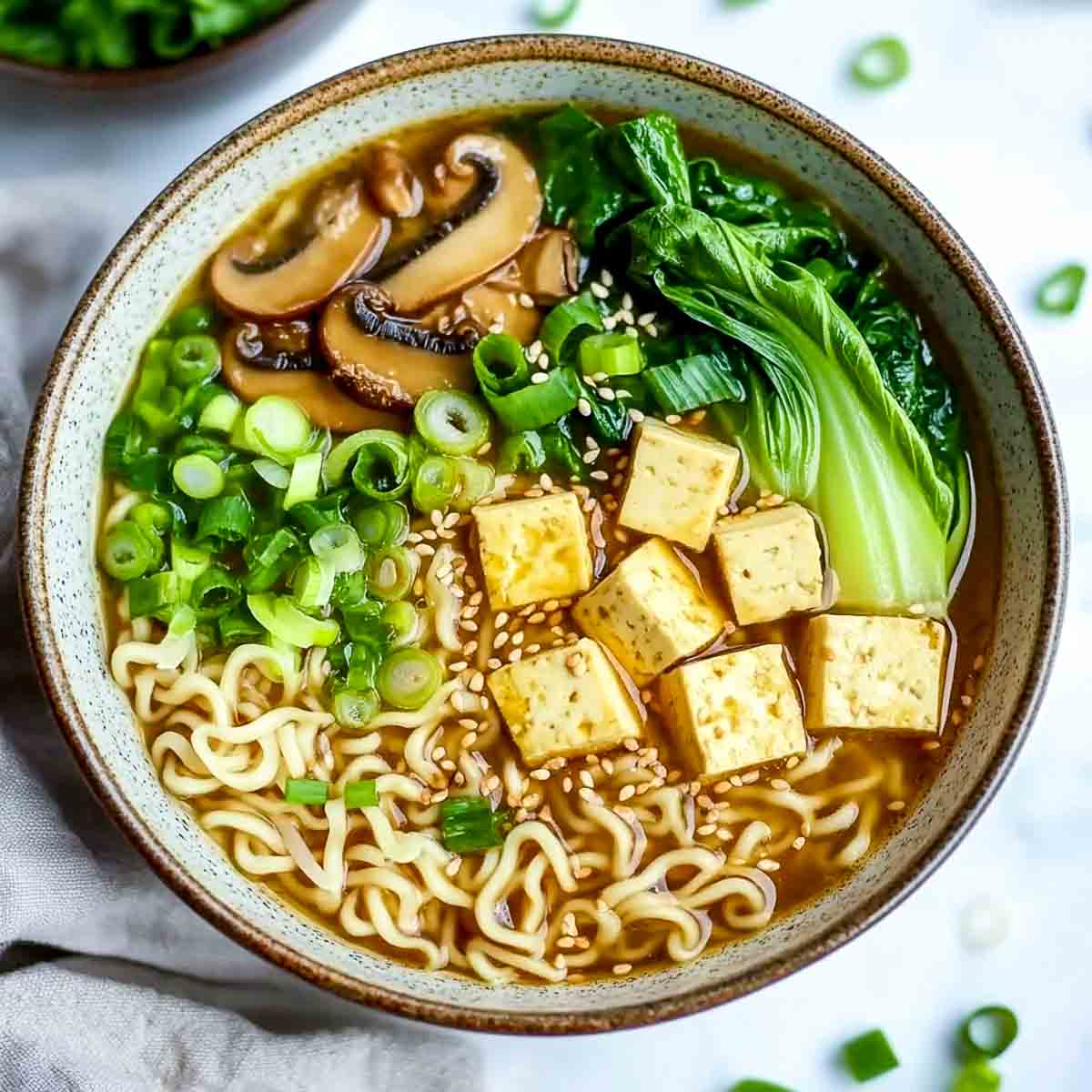 Miso and tofu vegetable ramen bowl on a marble surface.