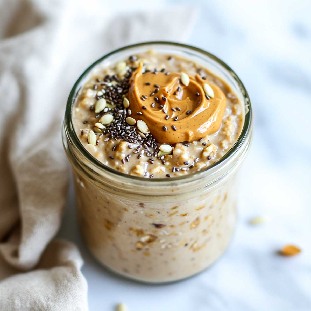 A jar of peanut butter oatmeal topped with chia seeds.